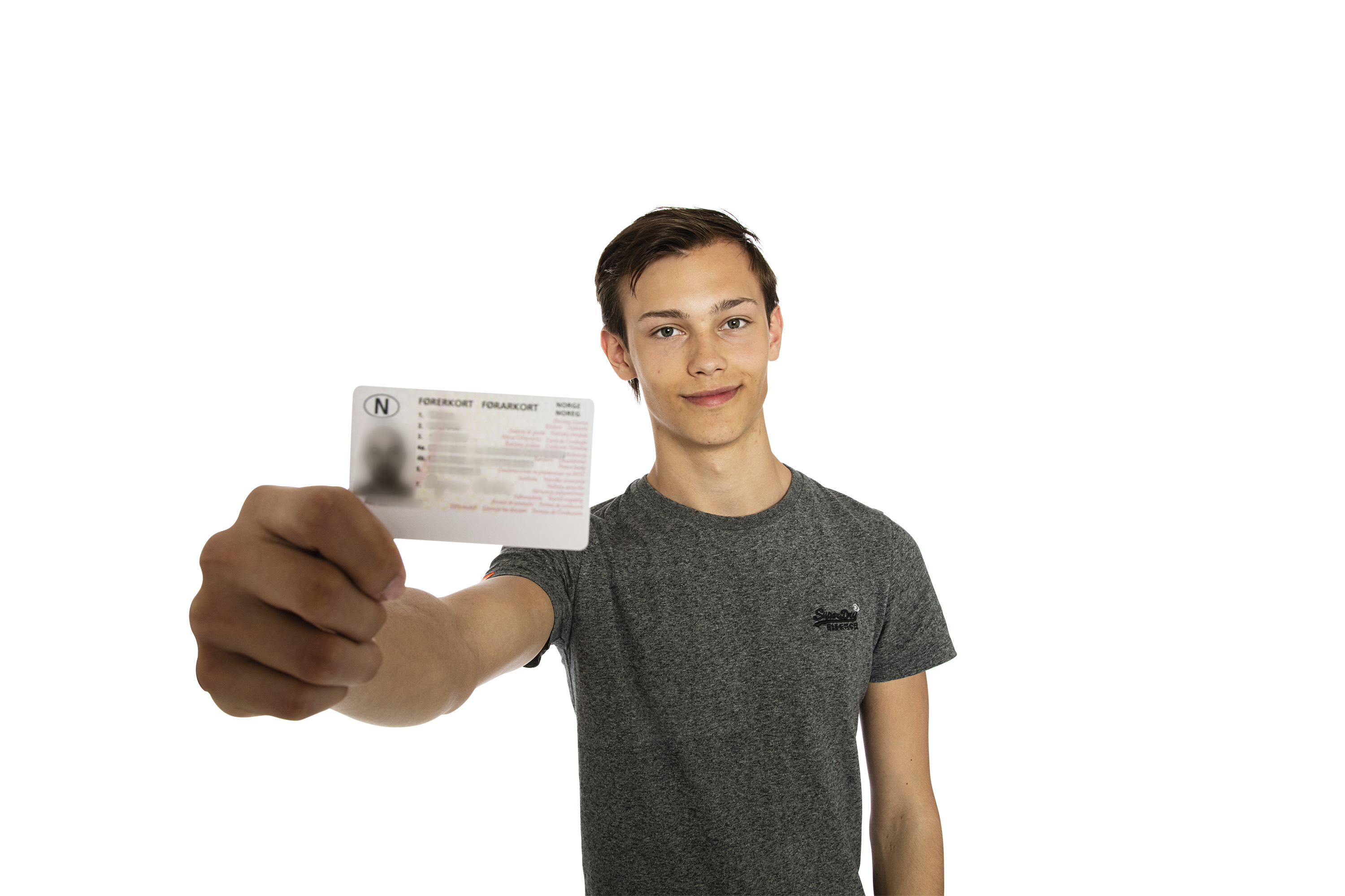 Fornøyd gutt viser frem førerkortet sitt. Tekst og tall på førerkortet er ikke lesbart og har blitt anonymisert.
