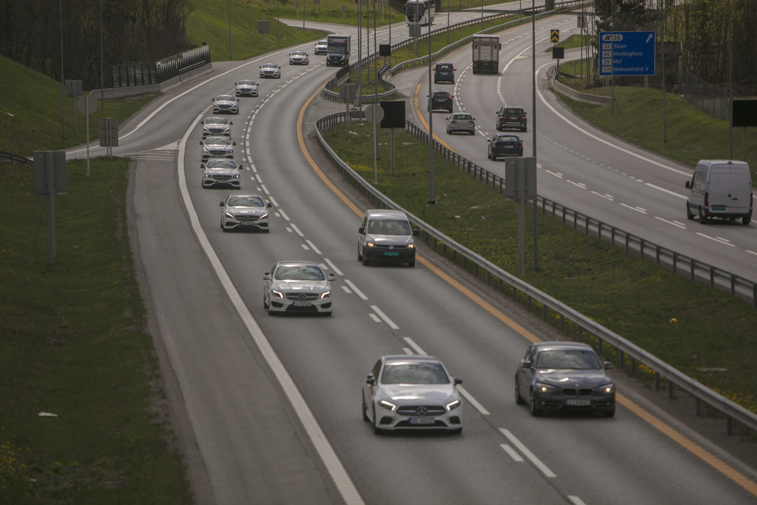 En rekke av Driving Trafikkskole sine biler som kjører i kortesje på motorveien.